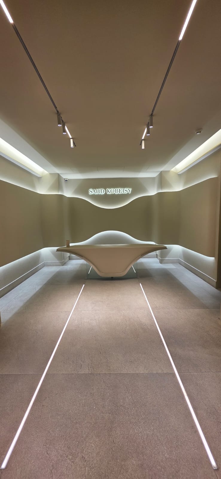 Sculptural reception desk under linear lighting in a couture showroom